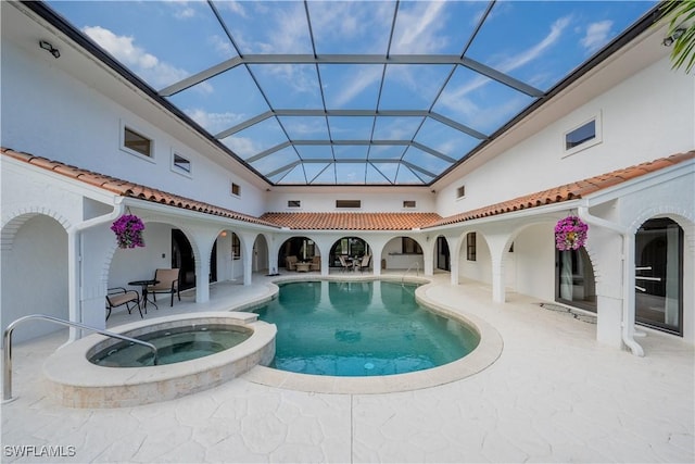 view of pool featuring a lanai, a pool with connected hot tub, and a patio