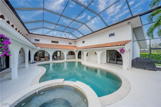 view of pool with glass enclosure, a patio area, and a pool with connected hot tub