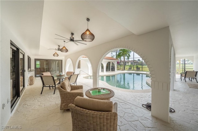 outdoor pool with glass enclosure, a ceiling fan, and a patio area