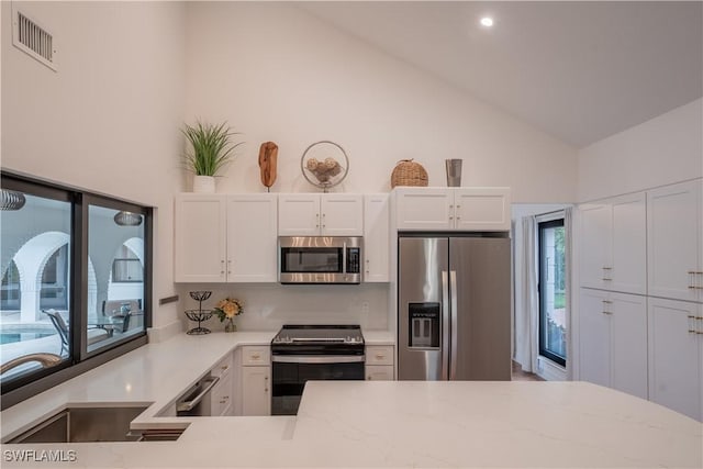 kitchen with white cabinetry, light stone counters, visible vents, and stainless steel appliances