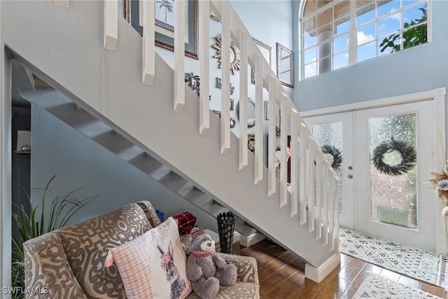 foyer entrance with baseboards, stairway, french doors, a towering ceiling, and wood finished floors