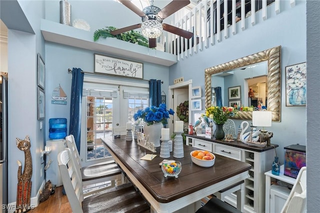 dining space with a ceiling fan, wood finished floors, a high ceiling, and french doors