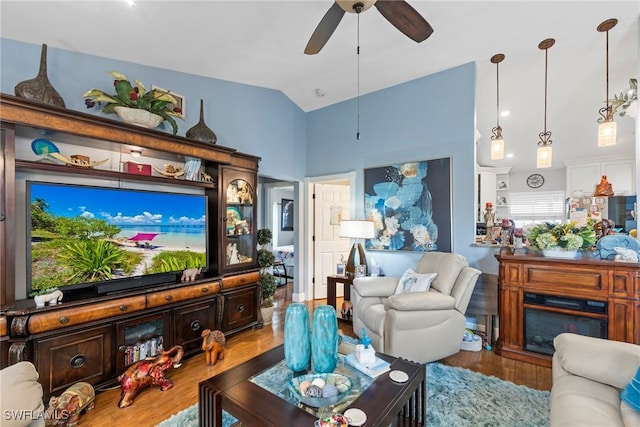 living room featuring a fireplace, wood finished floors, a ceiling fan, and vaulted ceiling