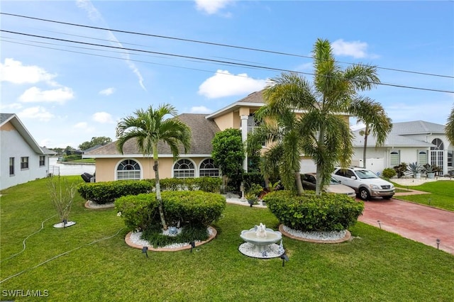 view of front of property with decorative driveway, roof with shingles, a front lawn, and stucco siding