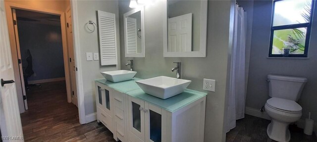 full bathroom with toilet, baseboards, a sink, and wood finished floors