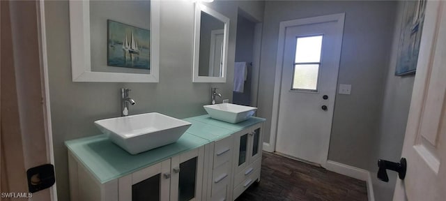 bathroom featuring double vanity, a sink, baseboards, and wood finished floors