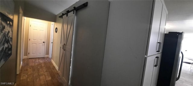 hallway featuring a barn door and wood finished floors