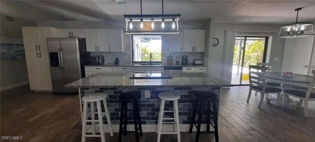 kitchen featuring appliances with stainless steel finishes, a center island, white cabinets, and dark wood-style floors