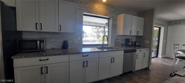 kitchen with visible vents, white cabinets, appliances with stainless steel finishes, light stone counters, and a sink