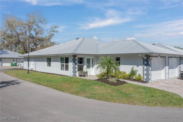 ranch-style home with a garage, stucco siding, metal roof, and a front yard