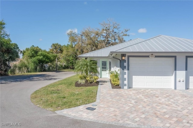 view of front of house with a garage, stucco siding, metal roof, and a standing seam roof