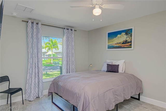 bedroom featuring visible vents, multiple windows, a ceiling fan, and baseboards