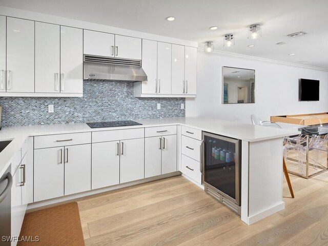 kitchen featuring beverage cooler, visible vents, a peninsula, black electric cooktop, and under cabinet range hood