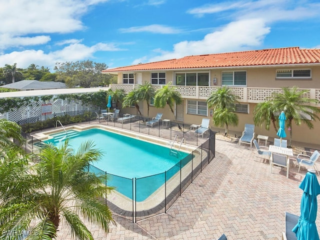 community pool featuring fence and a patio