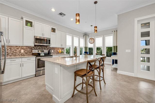 kitchen featuring visible vents, a sink, stainless steel appliances, crown molding, and backsplash