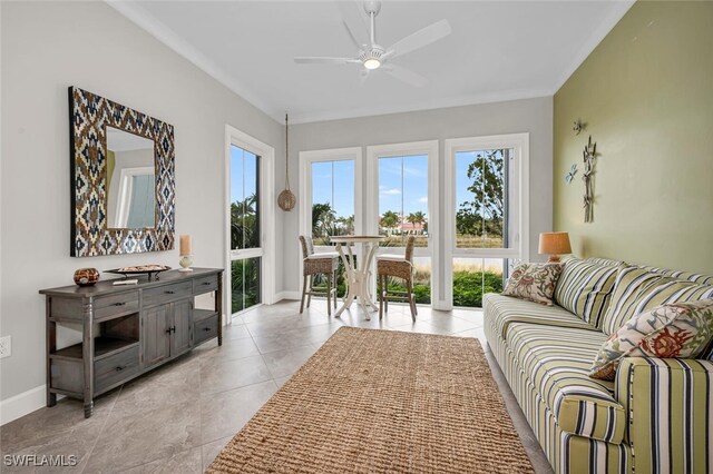 interior space with baseboards, light tile patterned flooring, a ceiling fan, and crown molding