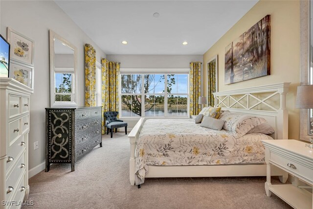 carpeted bedroom with a water view, multiple windows, baseboards, and recessed lighting