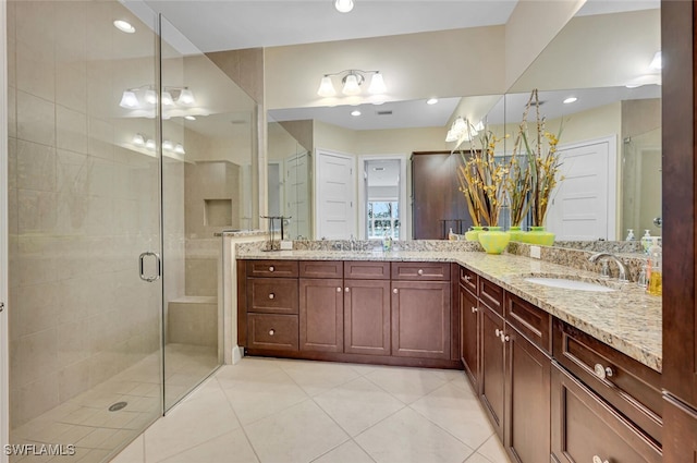 full bathroom featuring double vanity, a stall shower, tile patterned flooring, and a sink