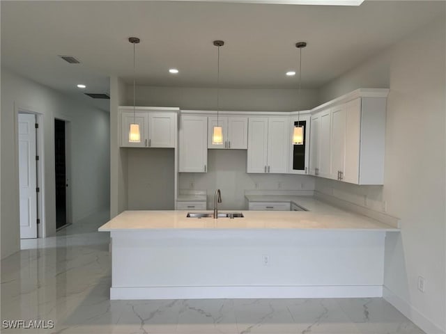 kitchen featuring a peninsula, recessed lighting, a sink, white cabinetry, and marble finish floor