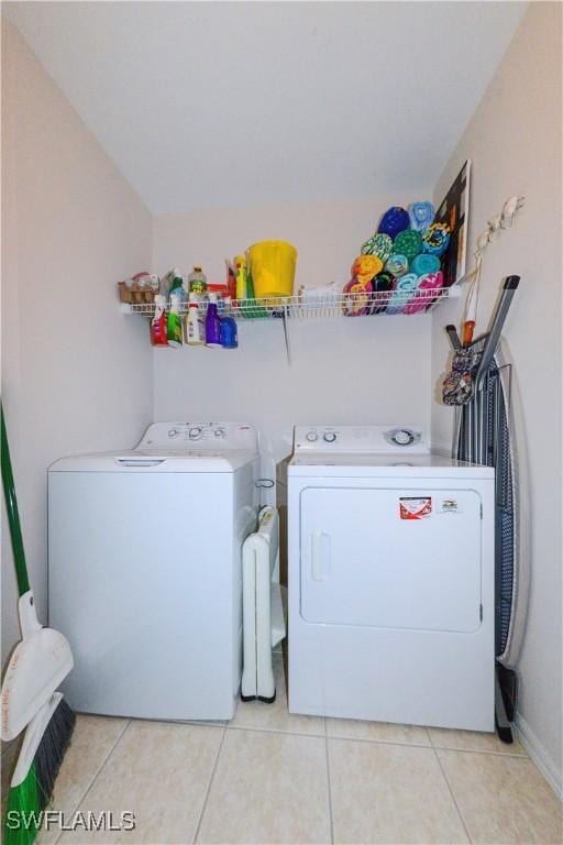 clothes washing area featuring laundry area, light tile patterned flooring, and independent washer and dryer