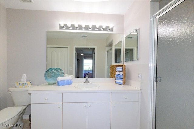 bathroom with a stall shower, visible vents, vanity, and toilet