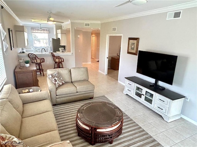 living room with light tile patterned floors, ceiling fan, visible vents, and crown molding