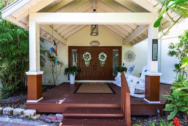 entrance to property featuring covered porch and stucco siding