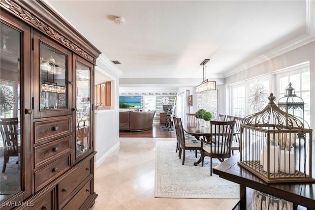 dining space featuring baseboards, ornamental molding, visible vents, and an inviting chandelier