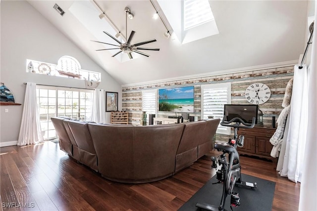 living room with a skylight, dark wood finished floors, visible vents, a ceiling fan, and high vaulted ceiling