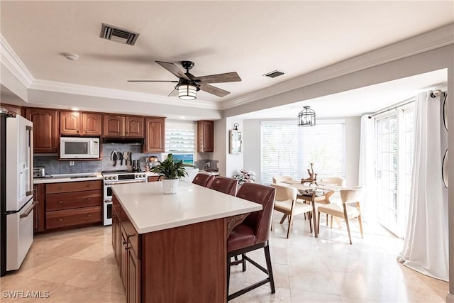 kitchen with white appliances, visible vents, light countertops, and a kitchen breakfast bar