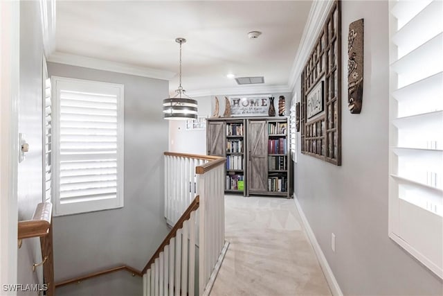 hallway featuring visible vents, baseboards, ornamental molding, carpet, and an upstairs landing