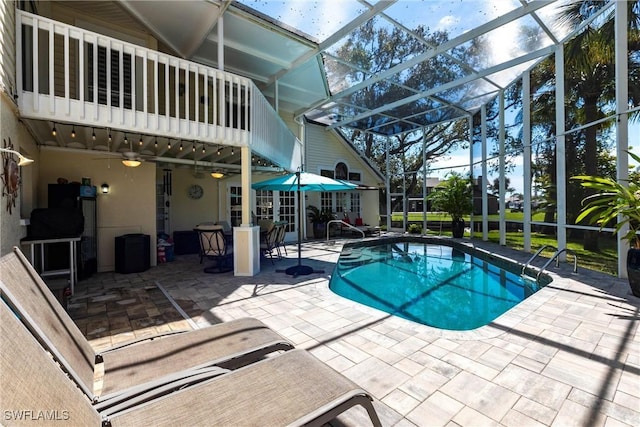 outdoor pool with a lanai, a patio area, and a ceiling fan