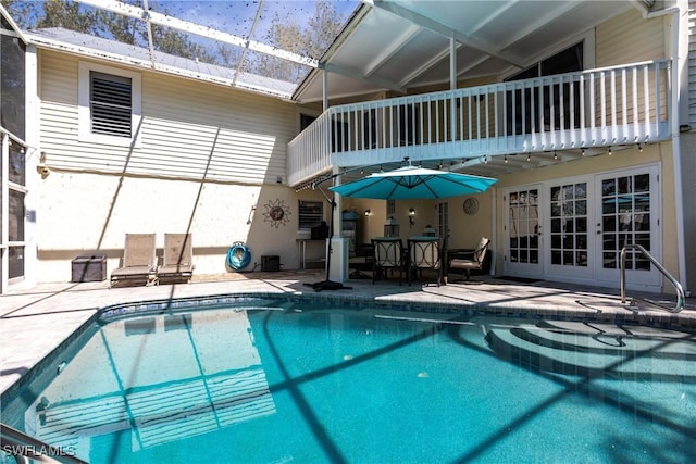 outdoor pool featuring a patio, french doors, and glass enclosure