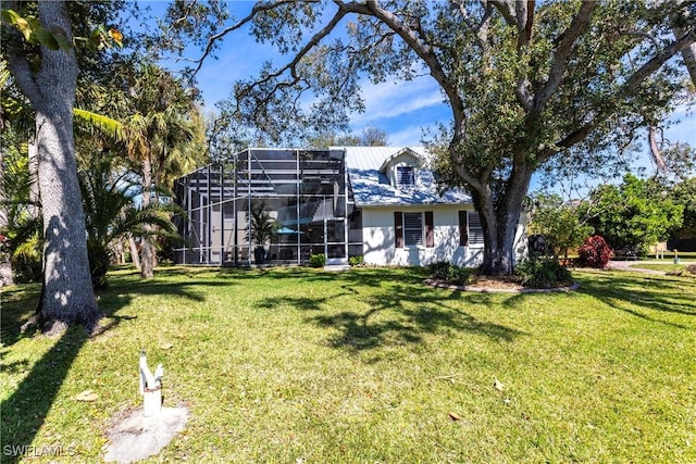 view of front of house featuring glass enclosure and a front yard