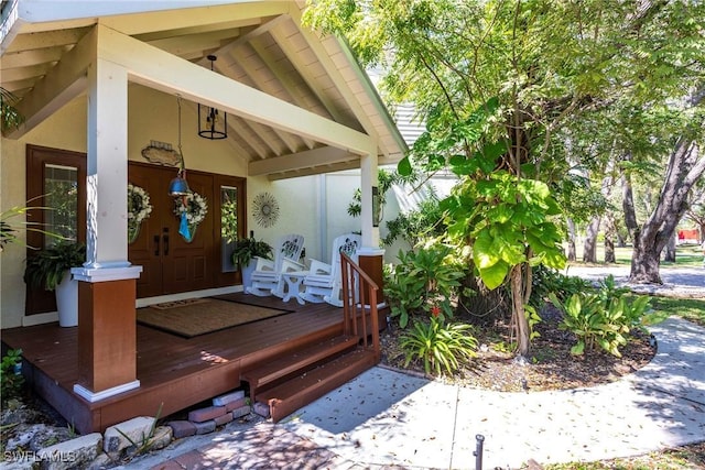 doorway to property featuring covered porch and stucco siding