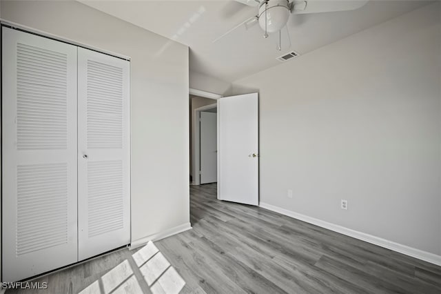 unfurnished bedroom featuring wood finished floors, a ceiling fan, visible vents, baseboards, and a closet