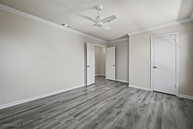 unfurnished bedroom with visible vents, ornamental molding, a ceiling fan, wood finished floors, and baseboards