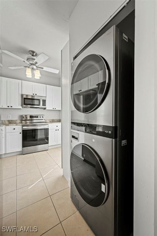 laundry room with light tile patterned floors, ceiling fan, laundry area, and stacked washer / drying machine