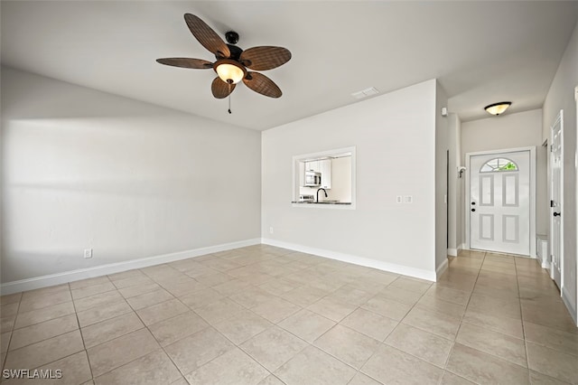 spare room with light tile patterned floors, ceiling fan, baseboards, and a sink