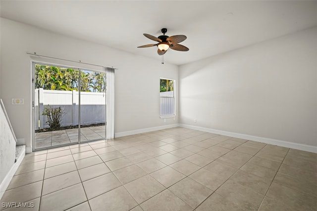 empty room featuring light tile patterned flooring, a ceiling fan, and baseboards