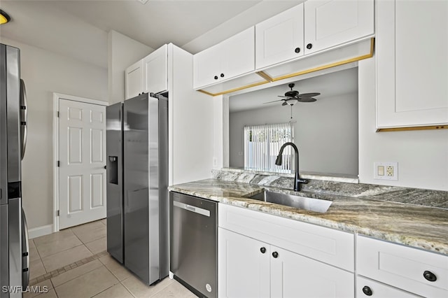 kitchen with light tile patterned floors, appliances with stainless steel finishes, light stone countertops, white cabinetry, and a sink