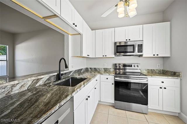 kitchen featuring stainless steel appliances, dark stone countertops, a sink, and white cabinetry