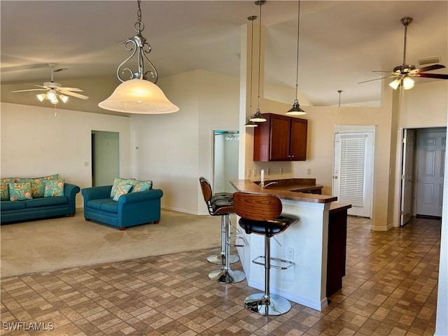 kitchen with open floor plan, carpet floors, a breakfast bar, and dark countertops