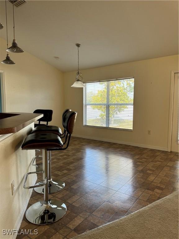 dining room with lofted ceiling, visible vents, and baseboards