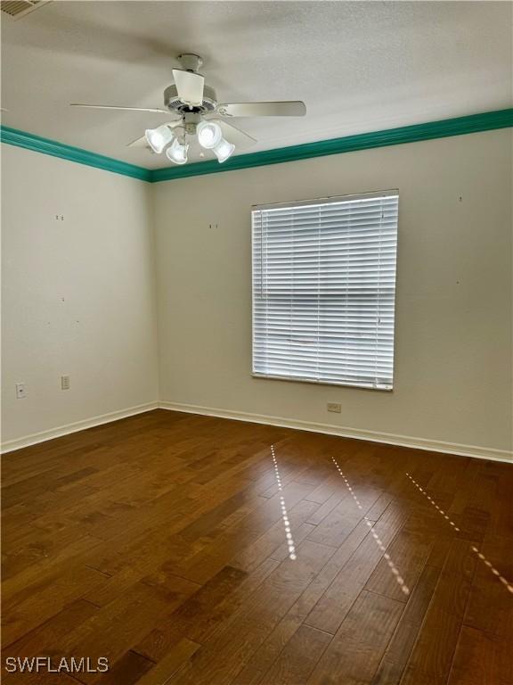 spare room featuring dark wood-style floors, baseboards, and a ceiling fan