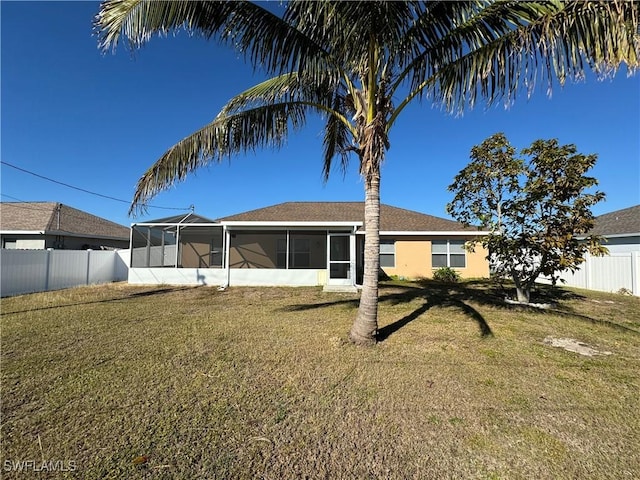 view of front of property featuring a sunroom, a fenced backyard, and a front lawn