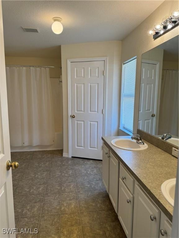 full bathroom with a sink, visible vents, tile patterned floors, double vanity, and shower / bath combo with shower curtain