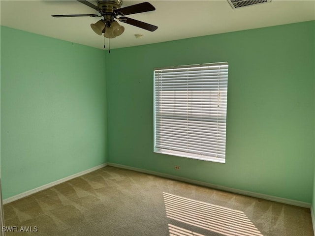 carpeted empty room with a ceiling fan, visible vents, and baseboards