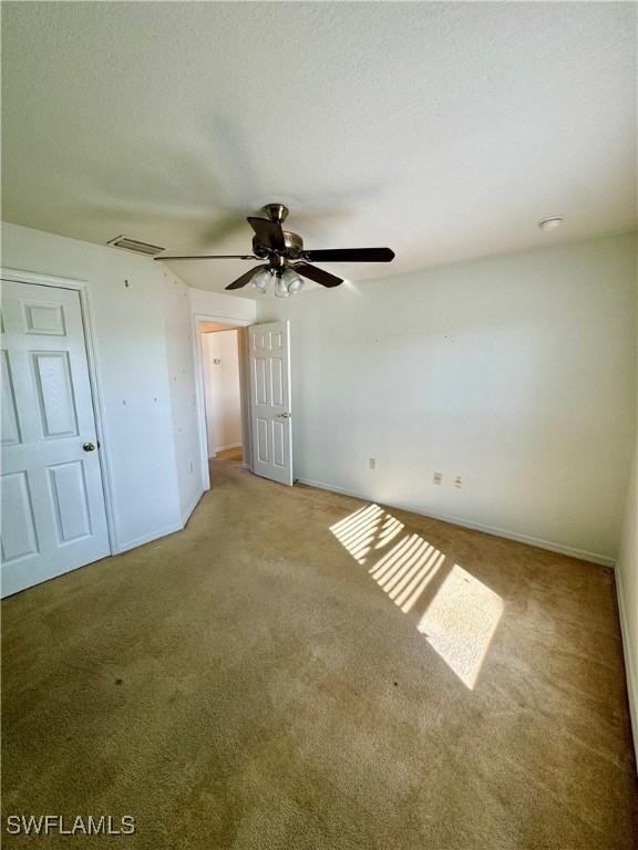 unfurnished bedroom with attic access, light carpet, a textured ceiling, and baseboards