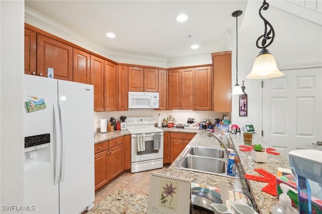 kitchen with hanging light fixtures, white appliances, brown cabinetry, and a sink